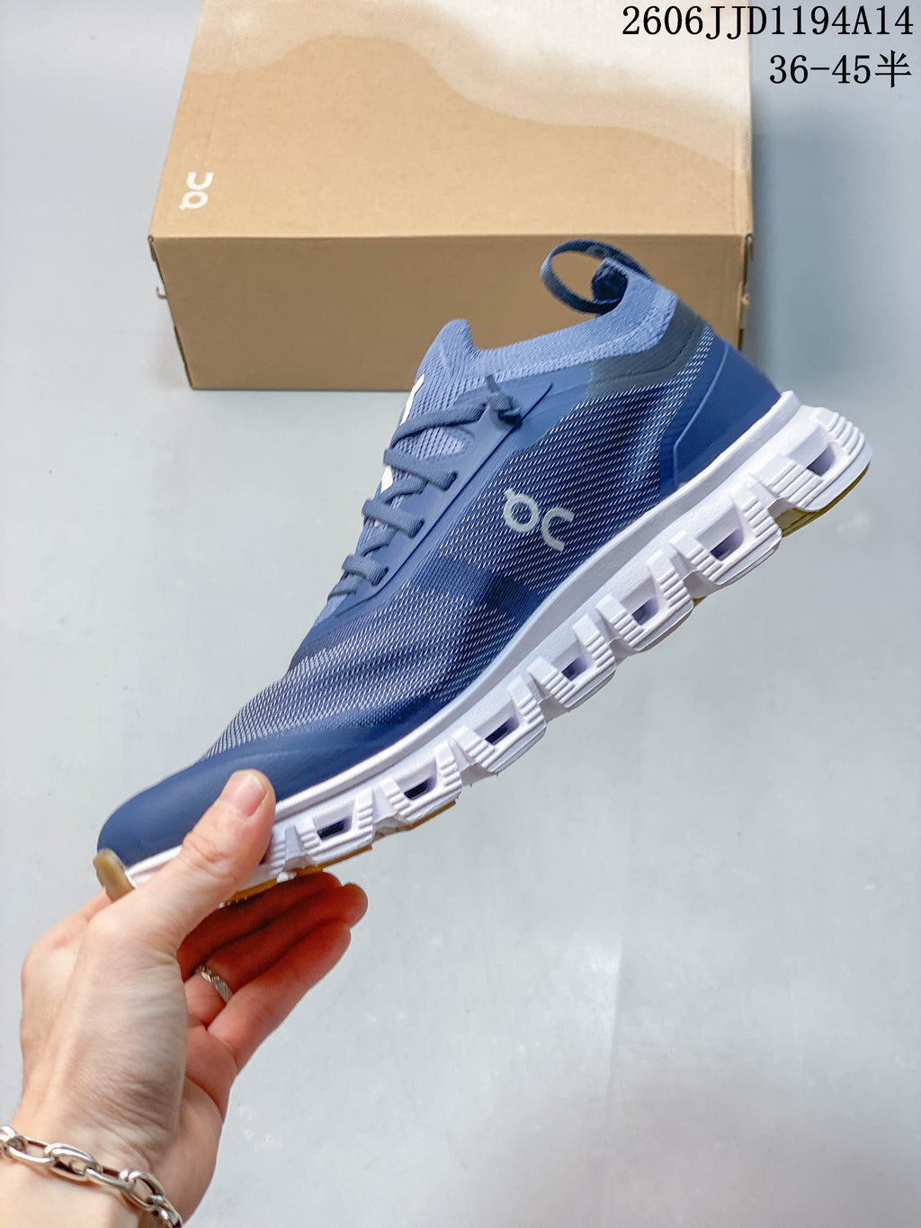 Side view of a blue On Cloud 6 Versa sneaker with patterned upper, heel pull tab and segmented white outsole.