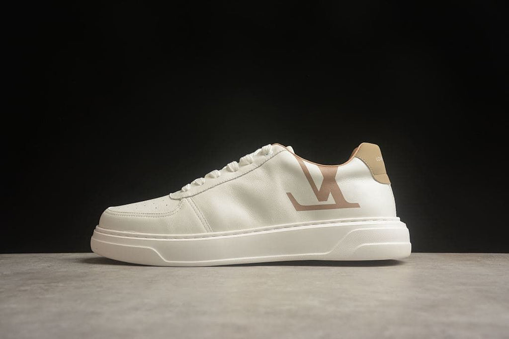 Side view of a cream low-top sneaker with tan accents and a large side logo