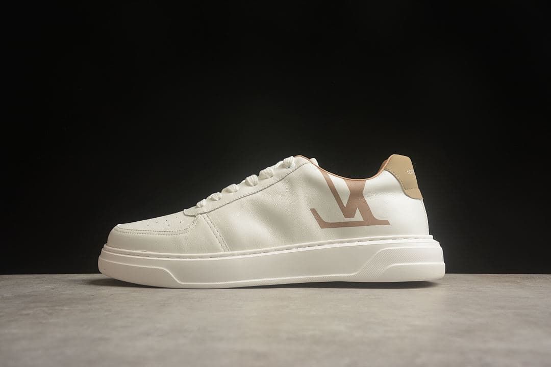 Side view of a cream low-top sneaker with tan accents and a large side logo