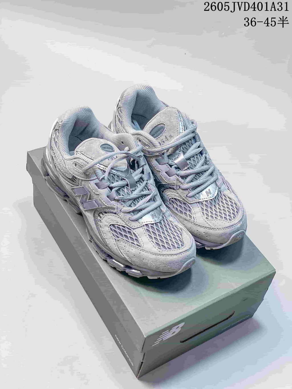 Pair of silver-gray New Balance 997 1954 Series sneakers on a shoebox.
