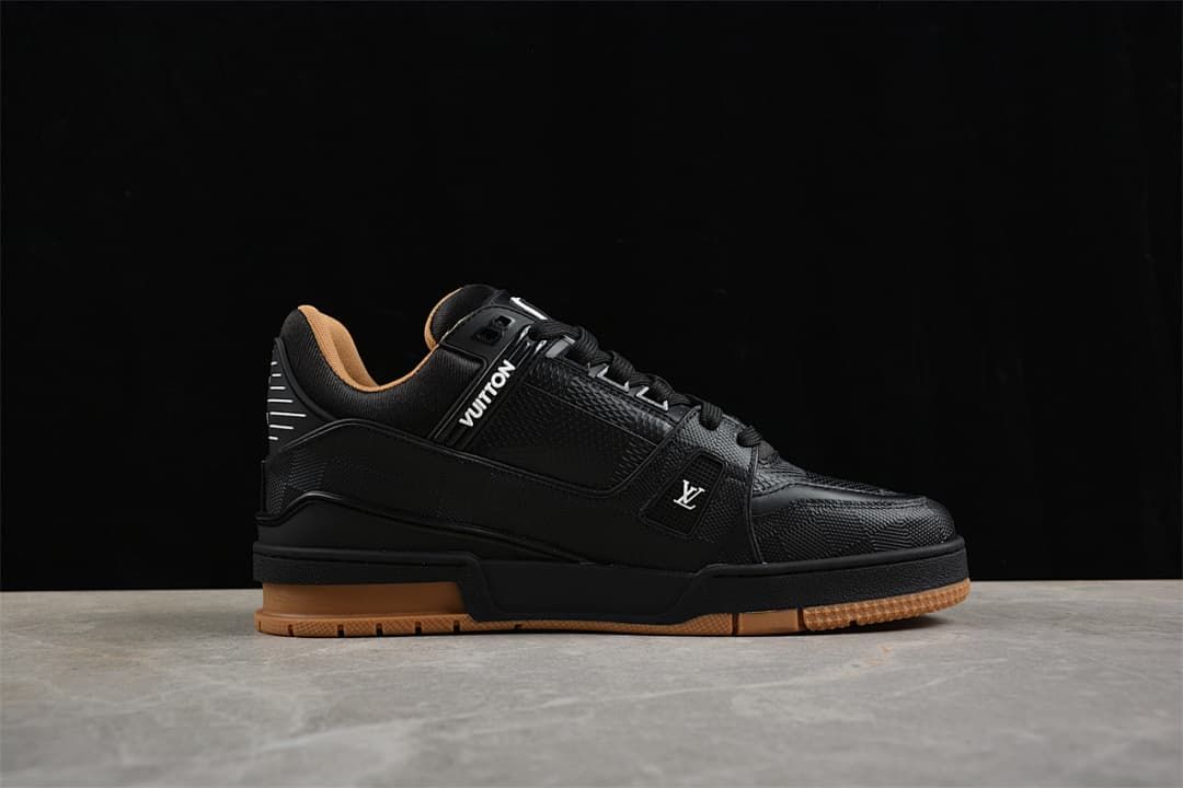Side view of a black low-top sneaker with logo details and a tan-colored outsole