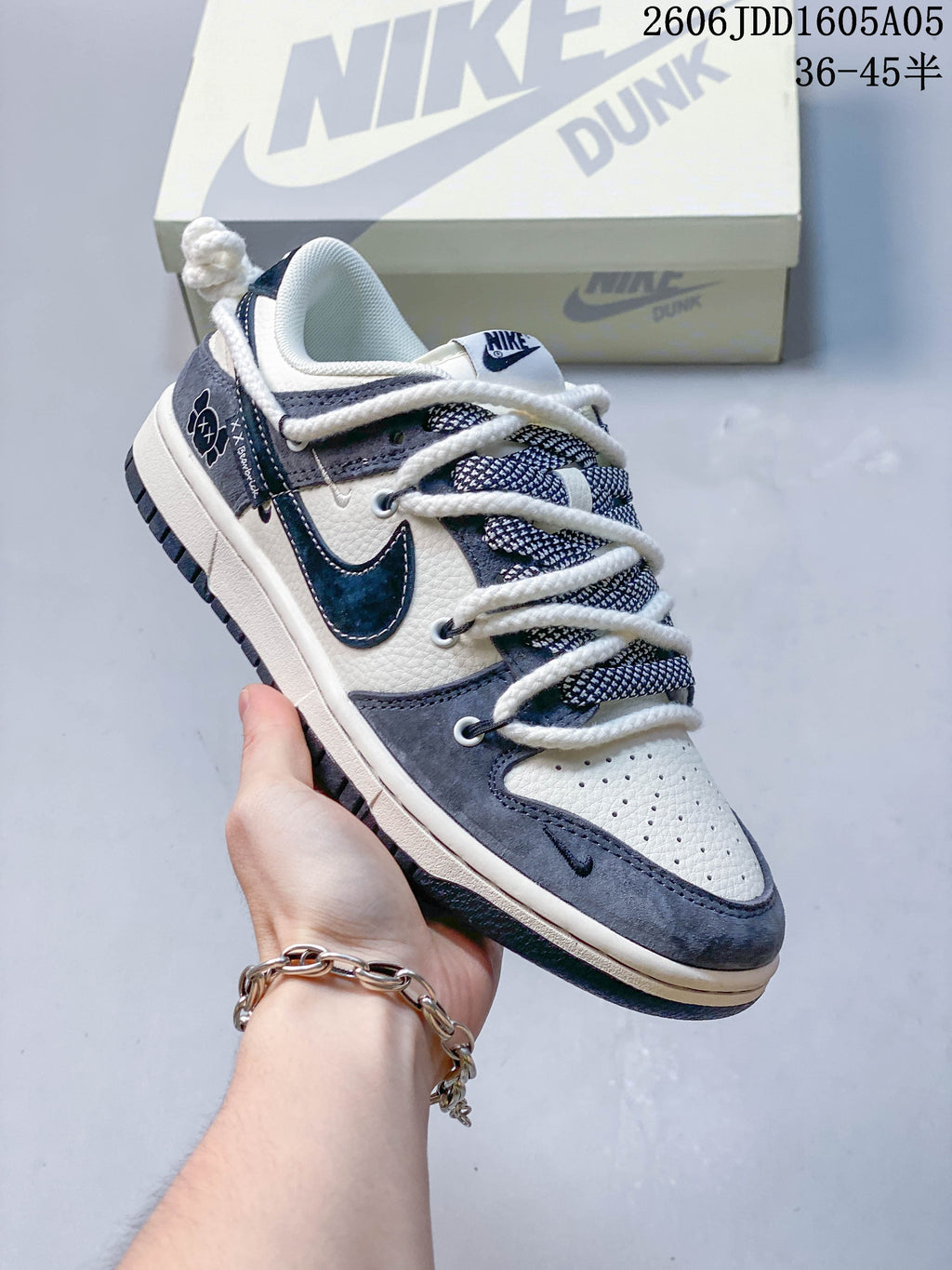 Gray and off-white low-top sneaker with dark accents, rope-style laces and a Nike Dunk box.