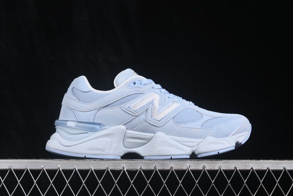 Side profile of light blue and white New Balance 9060 sneakers showing layered panels and sculpted midsole.