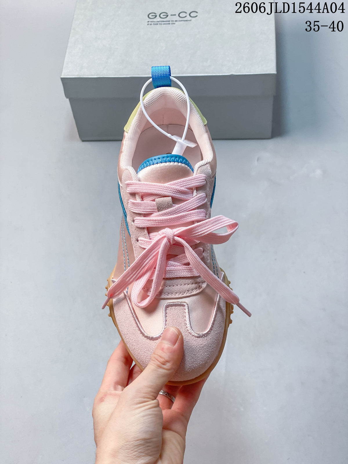 Top view of the pale pink lace-up sneaker, showing its T-shaped toe overlay and blue tongue accent.