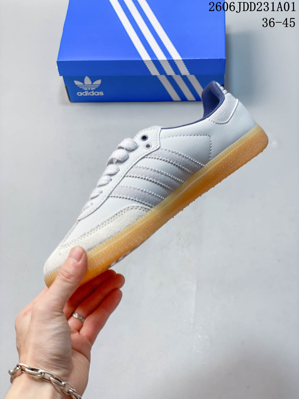 Side profile of a white low-top sneaker with gray stripes, navy collar accents, and gum-colored sole.
