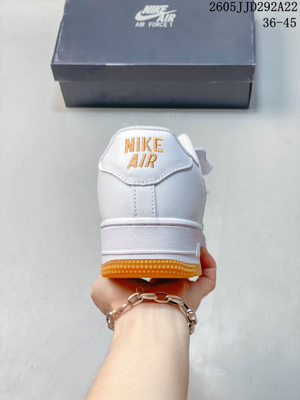 Rear view of the white sneaker with orange heel lettering and outsole