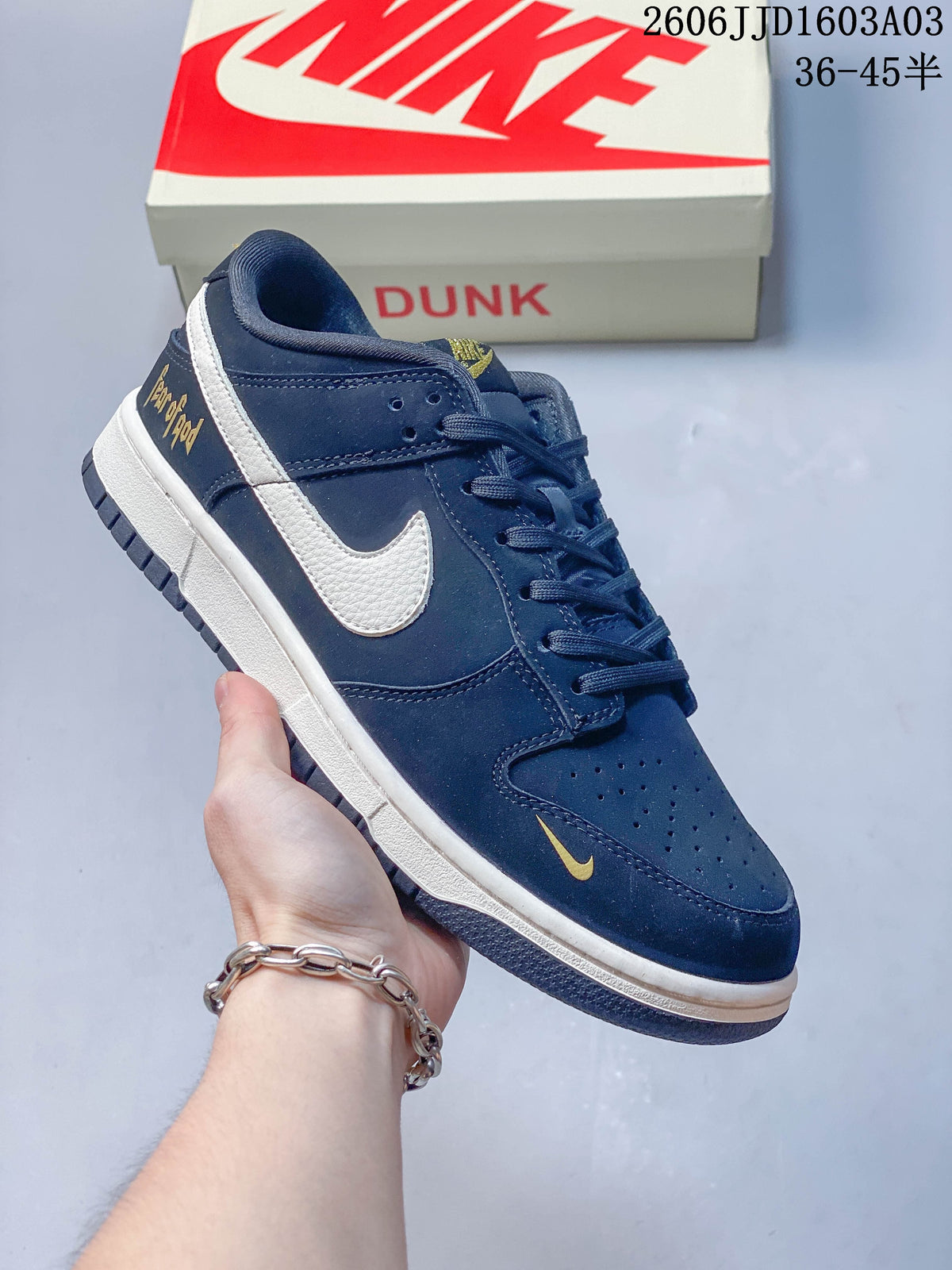 Angled side view showing the cream Swoosh and gold heel lettering on a navy Nike SB Dunk Low