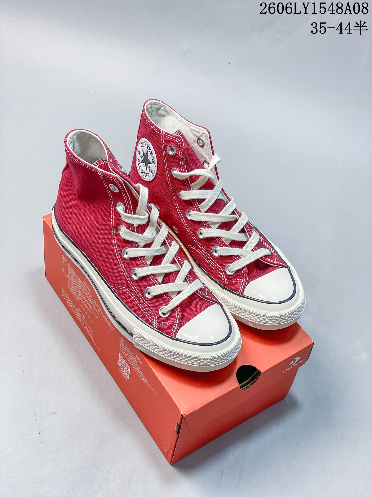 Pair of red Converse Chuck 70 high-top sneakers with white laces and off-white soles, shown on an orange shoe box.