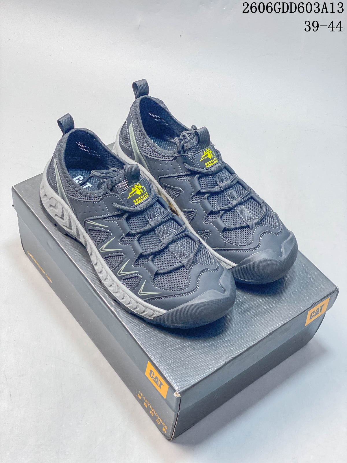 Pair of dark gray CAT lace-up sneakers with mesh panels and light-gray midsoles, shown on a CAT box
