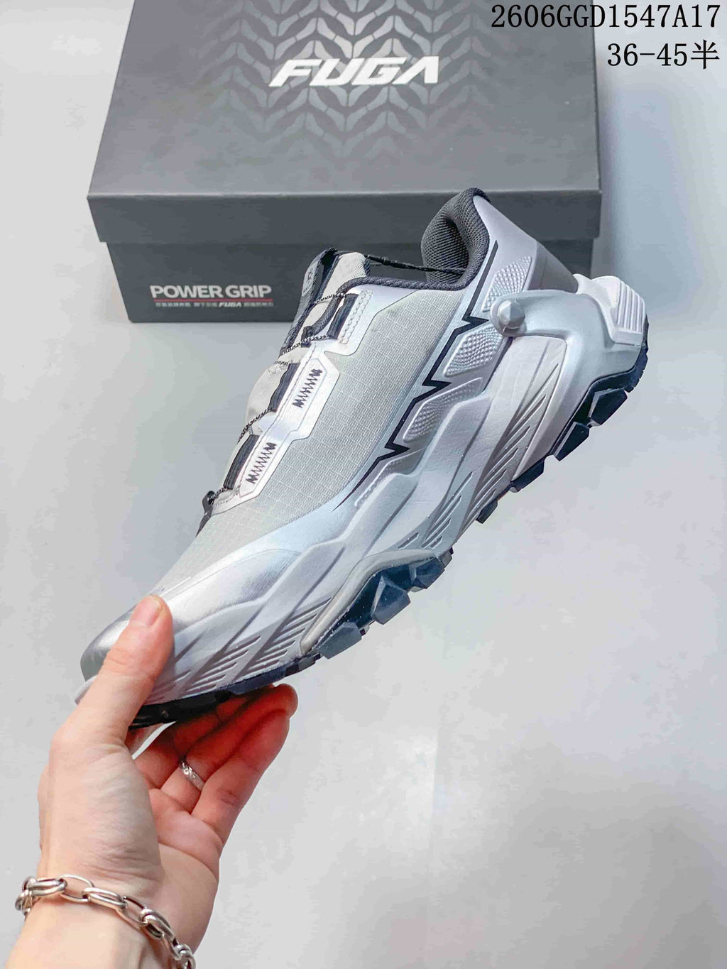Side profile of the silver-gray low-cut trail shoe with its lugged outsole and overlay details.