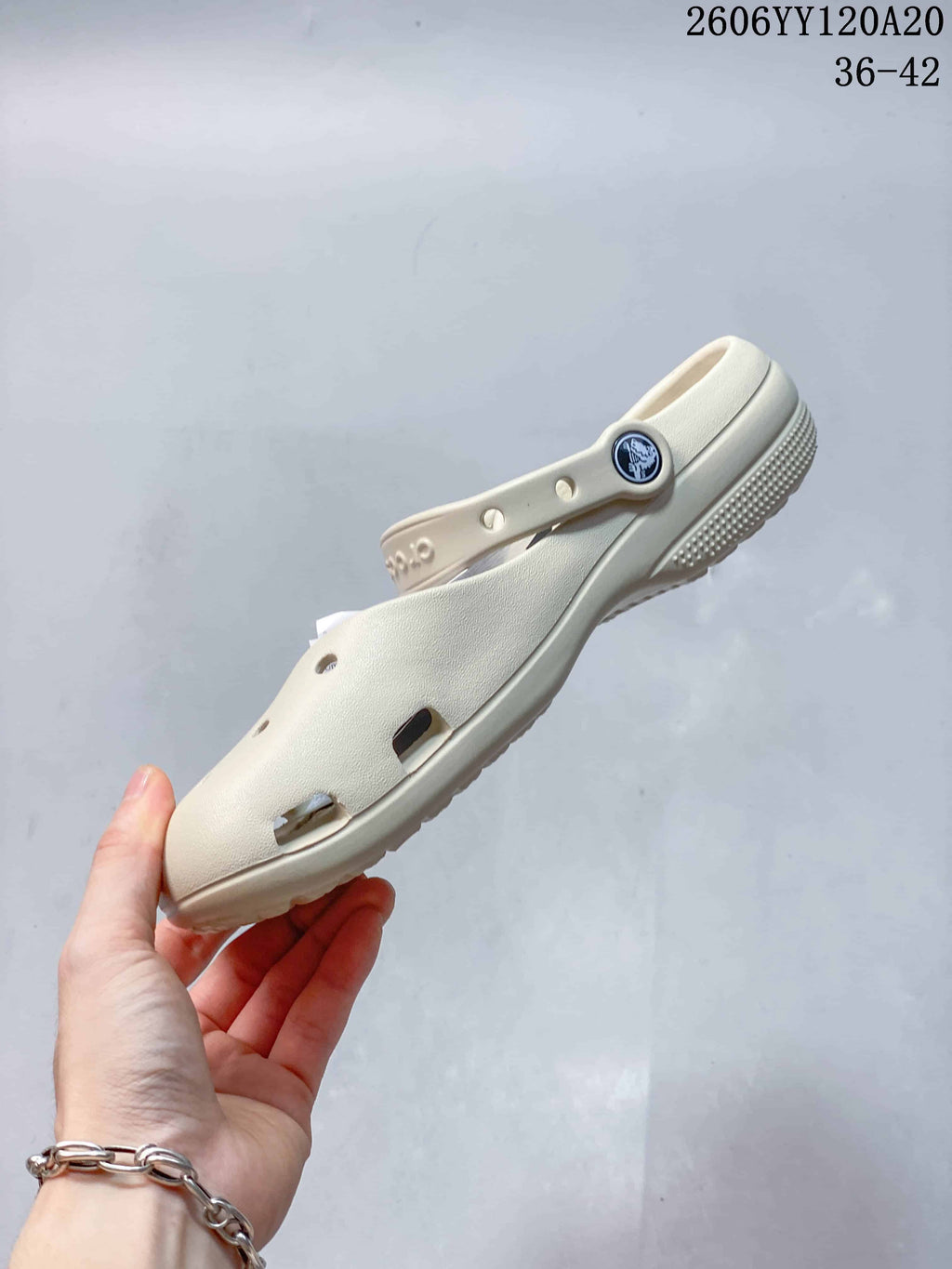 Side profile of the cream clog with perforated upper and pivoting heel strap.