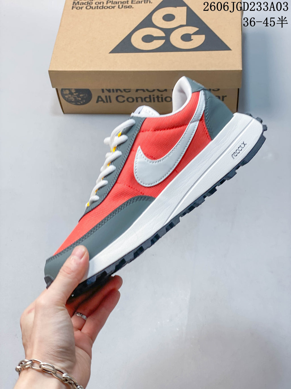 Side view of a coral-red and gray Nike ACG LDV shoe with white Swoosh detail