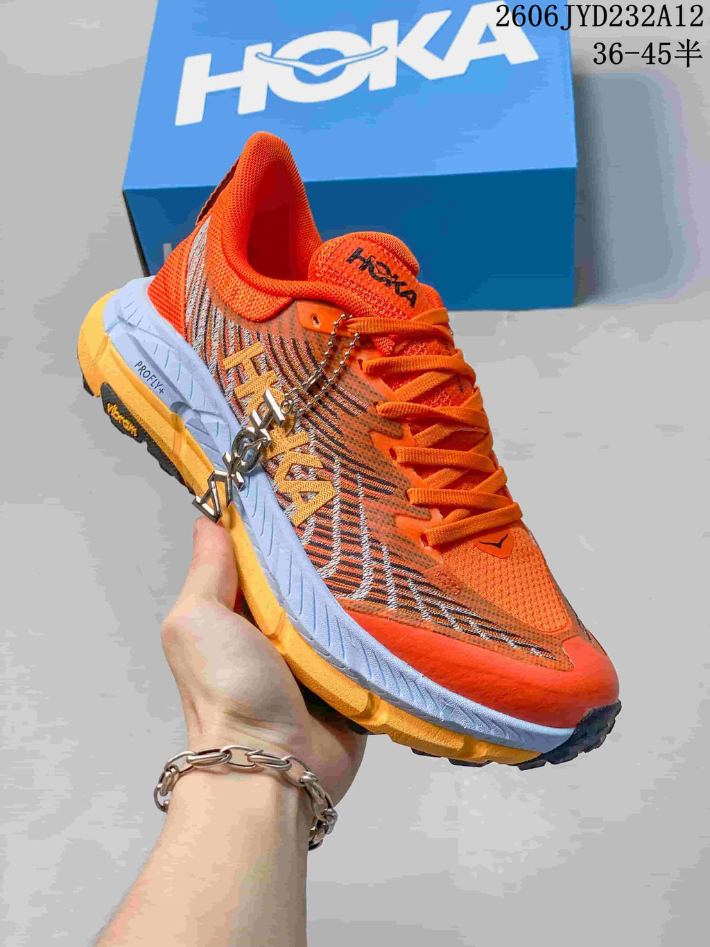 Angled side view of the orange HOKA shoe with patterned panels