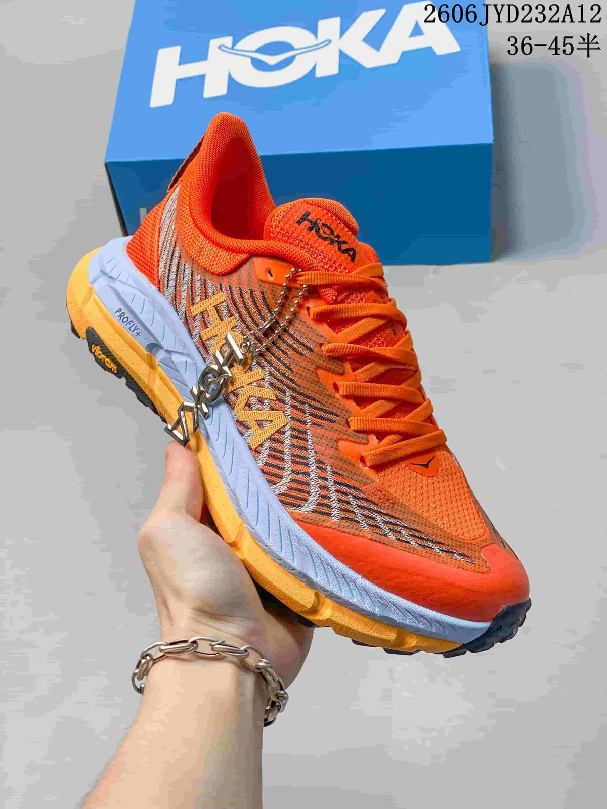 Angled side view of the orange HOKA shoe with patterned panels
