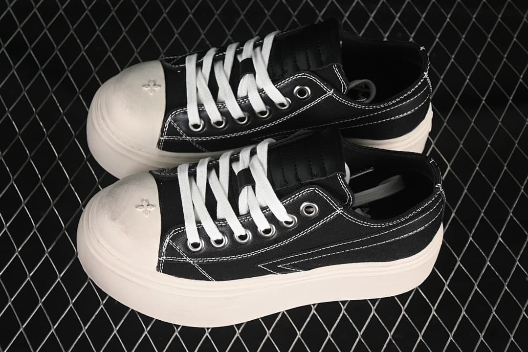 Pair of black low-top platform sneakers with white laces and contrast stitching.