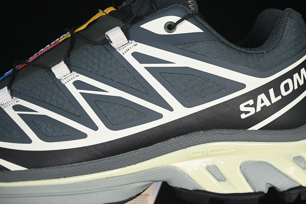 Close-up of the sneaker side, showing white overlays, dark gray upper, and pale midsole accents.