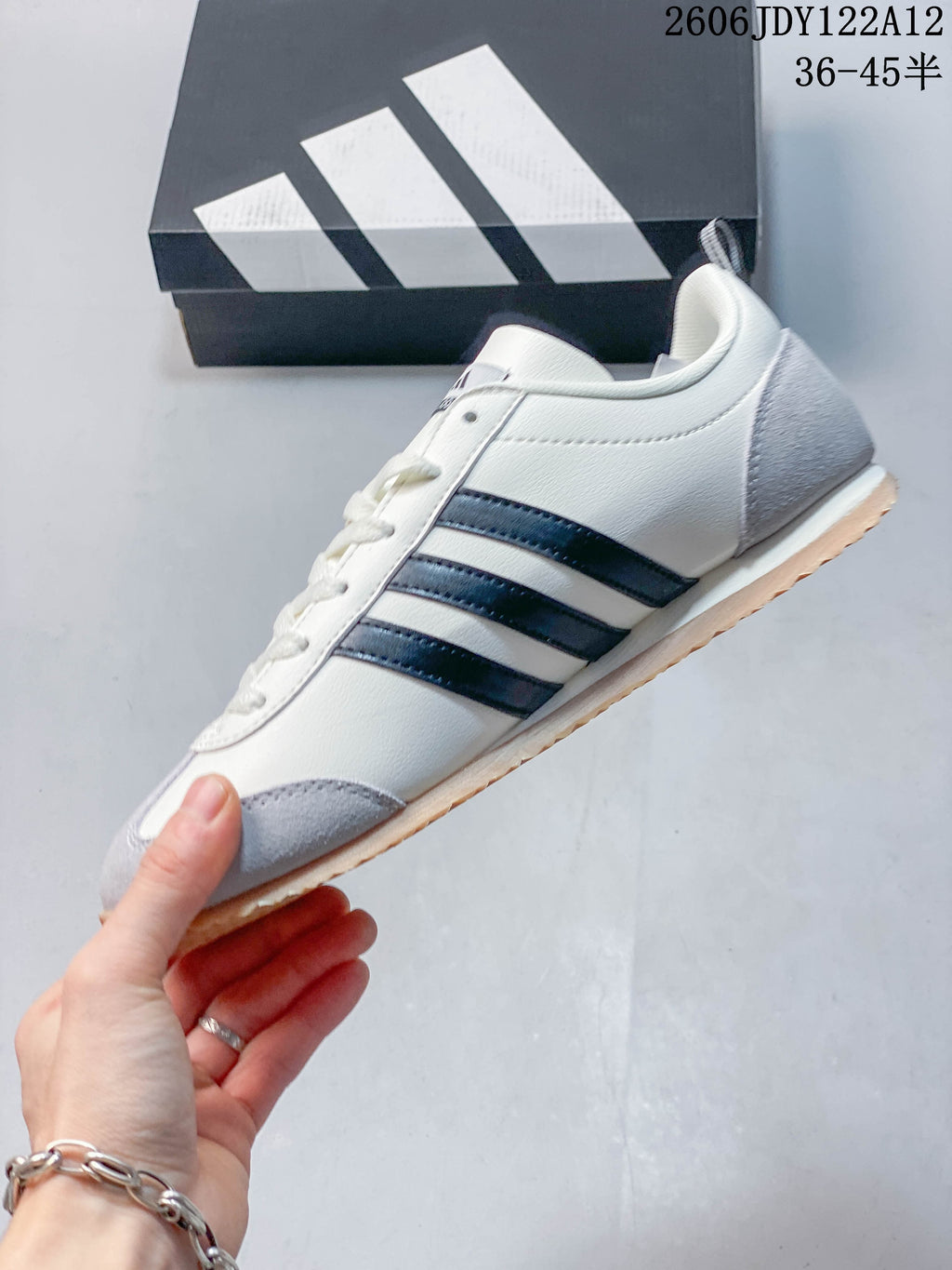 Side profile showing the white upper, dark stripes, gray overlays and gum-colored outsole.
