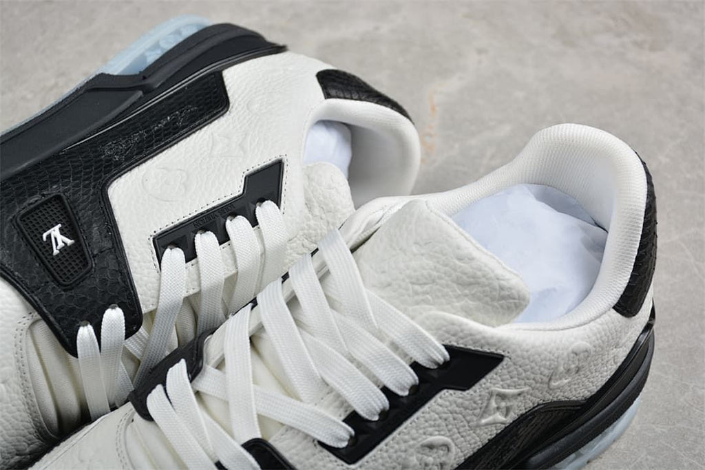 Close-up of the sneakers showing embossed detailing, white laces, and black overlays.