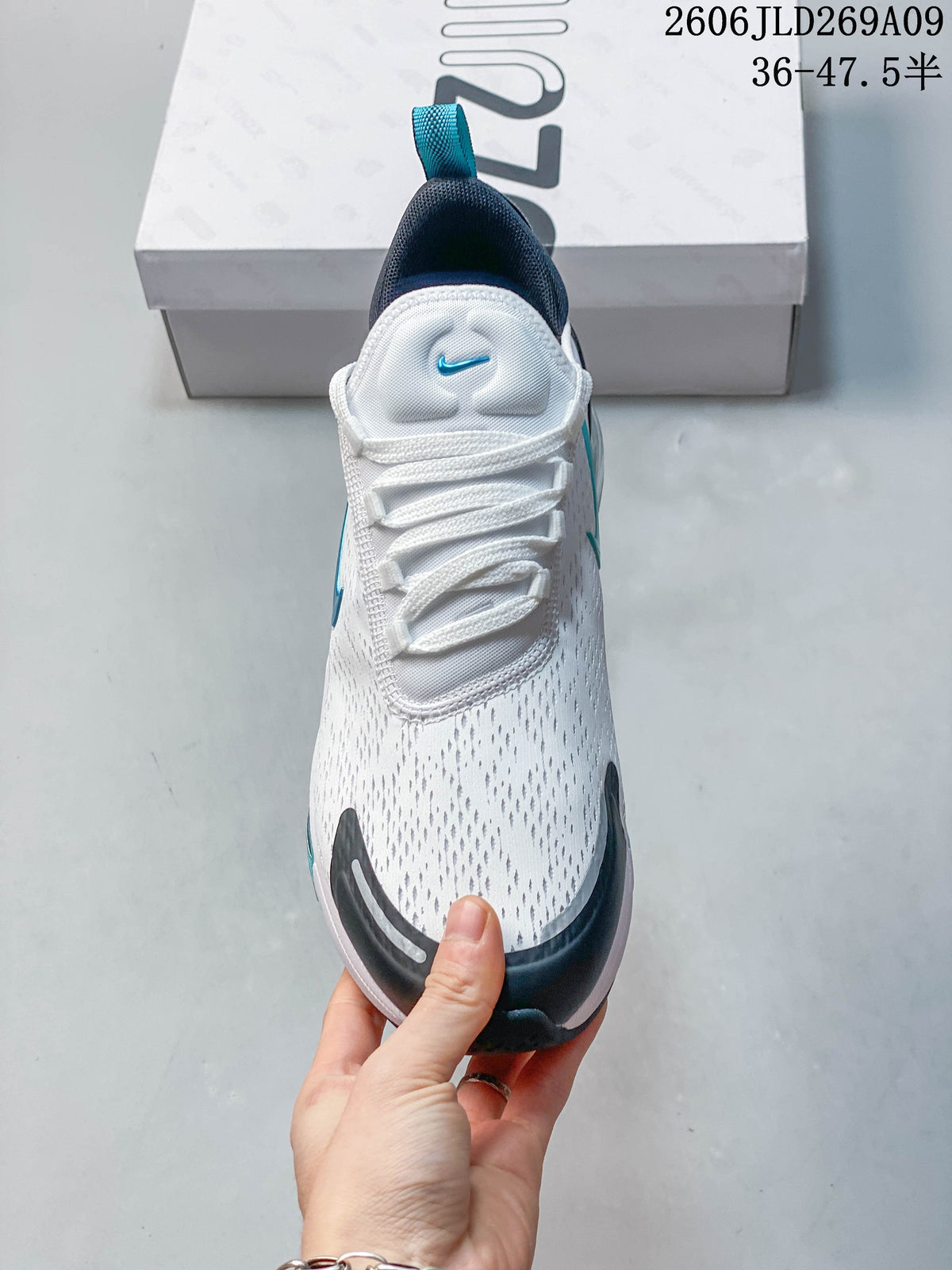 Front view of a white Nike Air Max 270 sneaker with dark toe accents and teal details