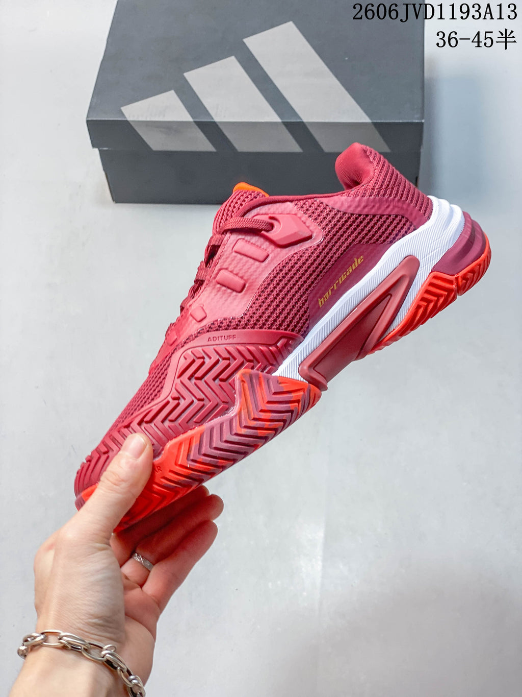 Side view of the red Adidas tennis shoe showing its mesh panels and outsole.