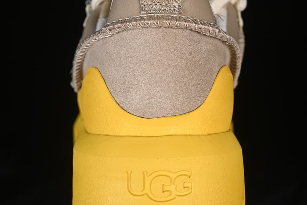 Rear view showing the taupe heel, yellow sole, and embossed UGG logo