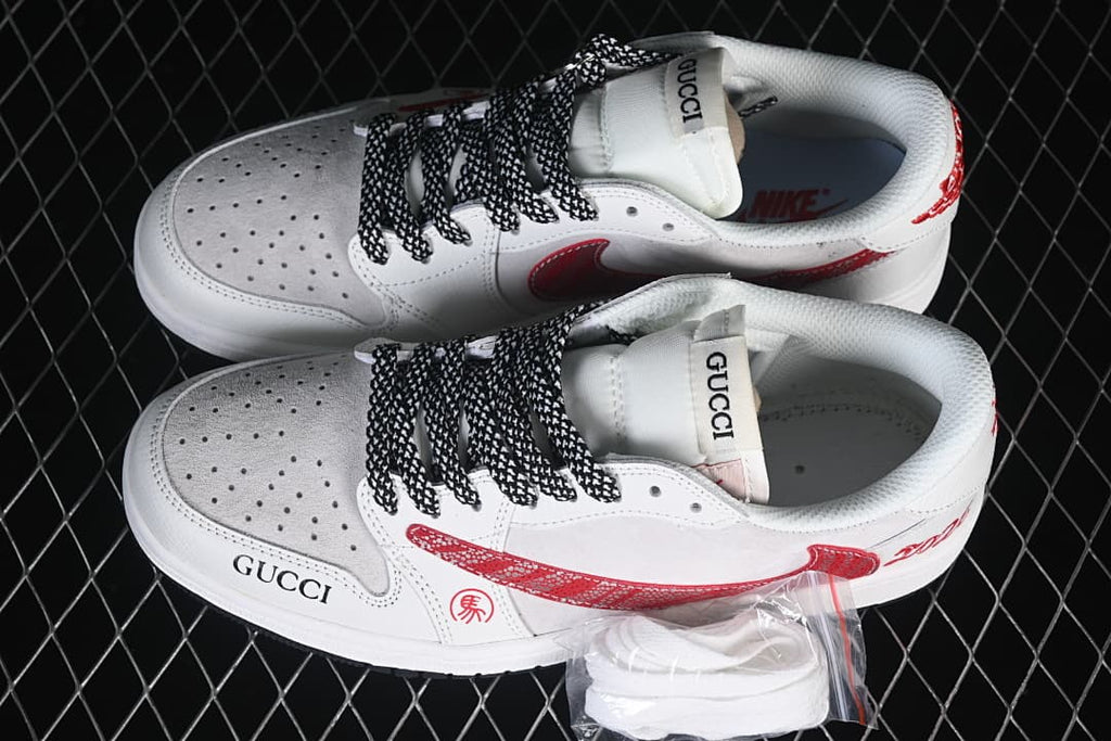 Top view of a pair of white low-top sneakers with red patterned side panels and black-and-white laces.