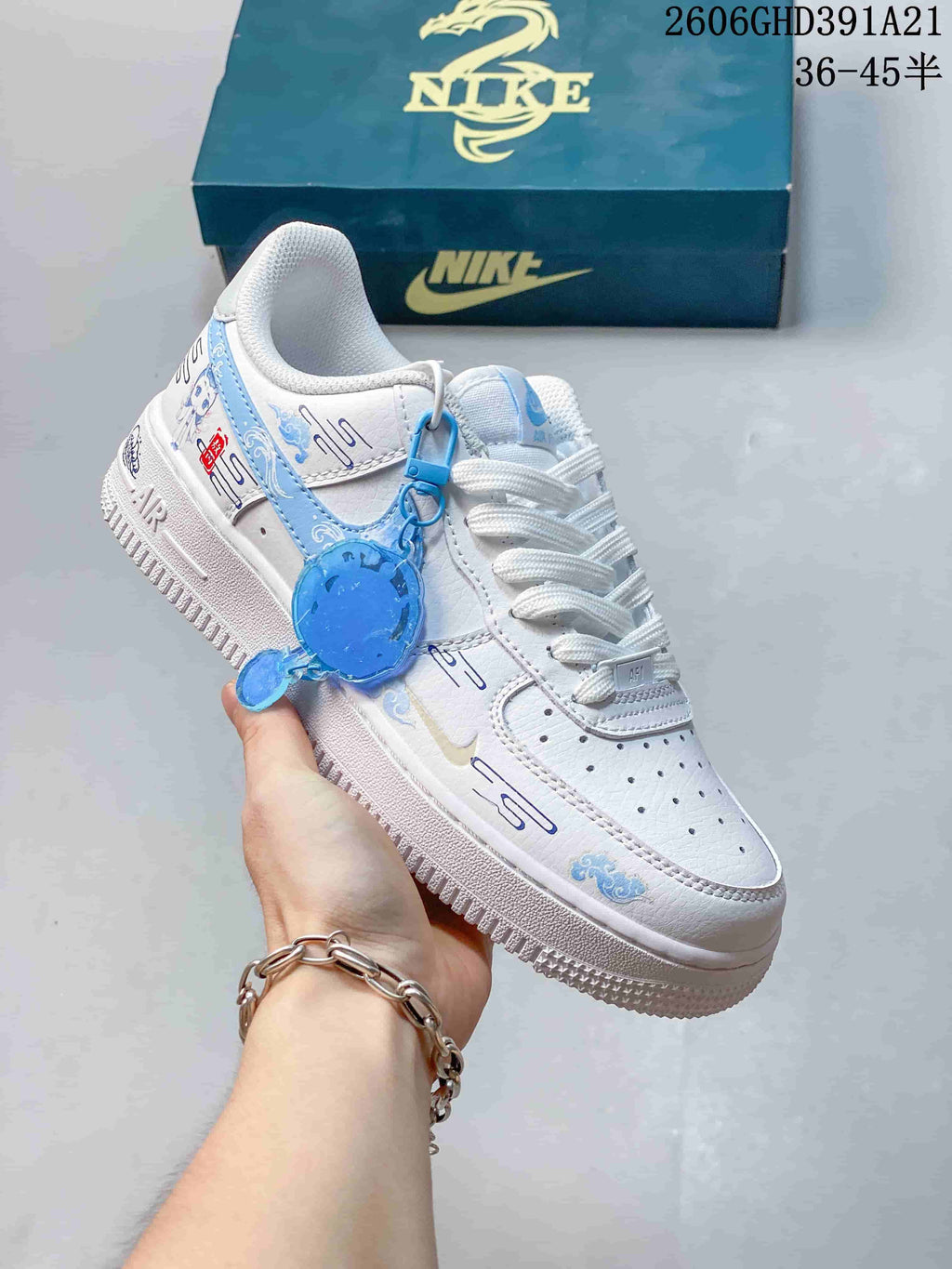 Angled view of the white sneaker with blue decorative details and a hanging charm.
