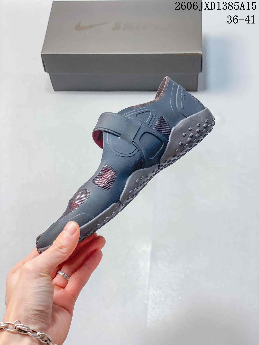 Side view of a dark gray Nike Air Rift shoe with mesh panels, a wide strap, and split-toe design.