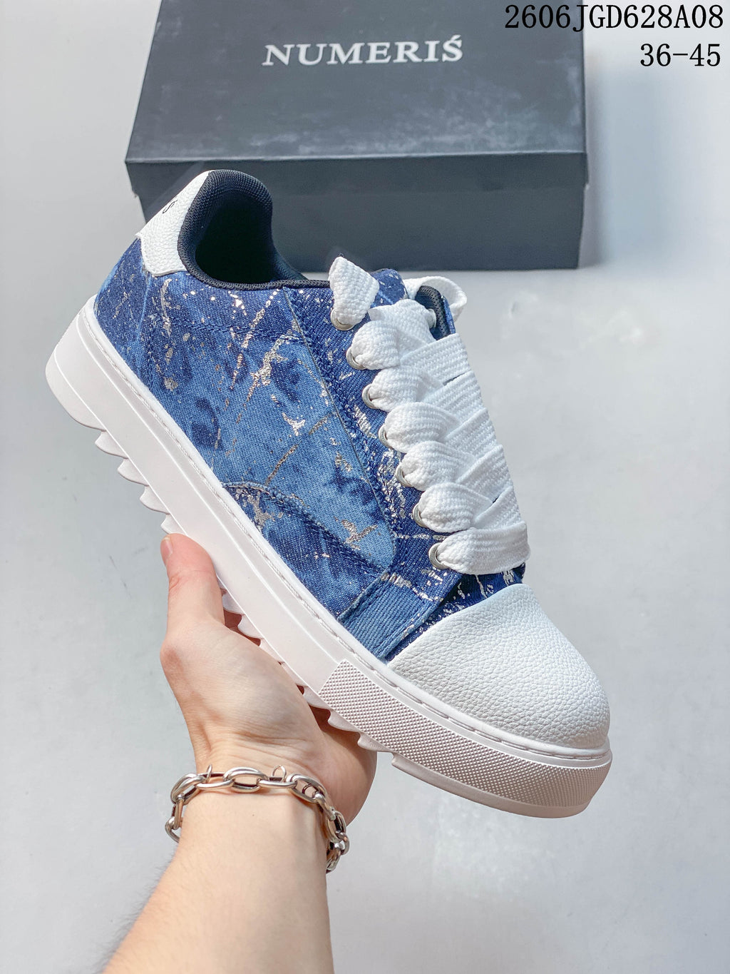 Blue sneaker with a white toe and sole and a splatter-pattern side panel.