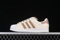 Side view of cream and brown adidas Superstar II sneakers against a black background.