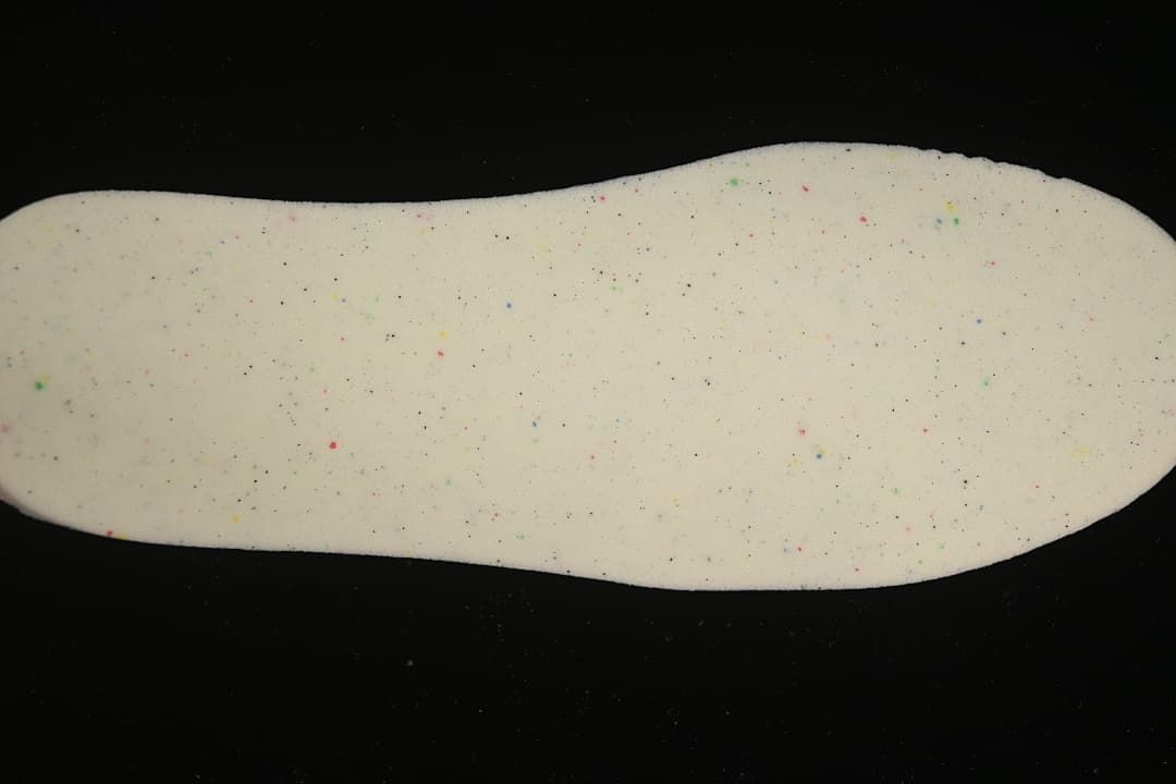 Close-up of a light-colored insole with small multicolored speckles.