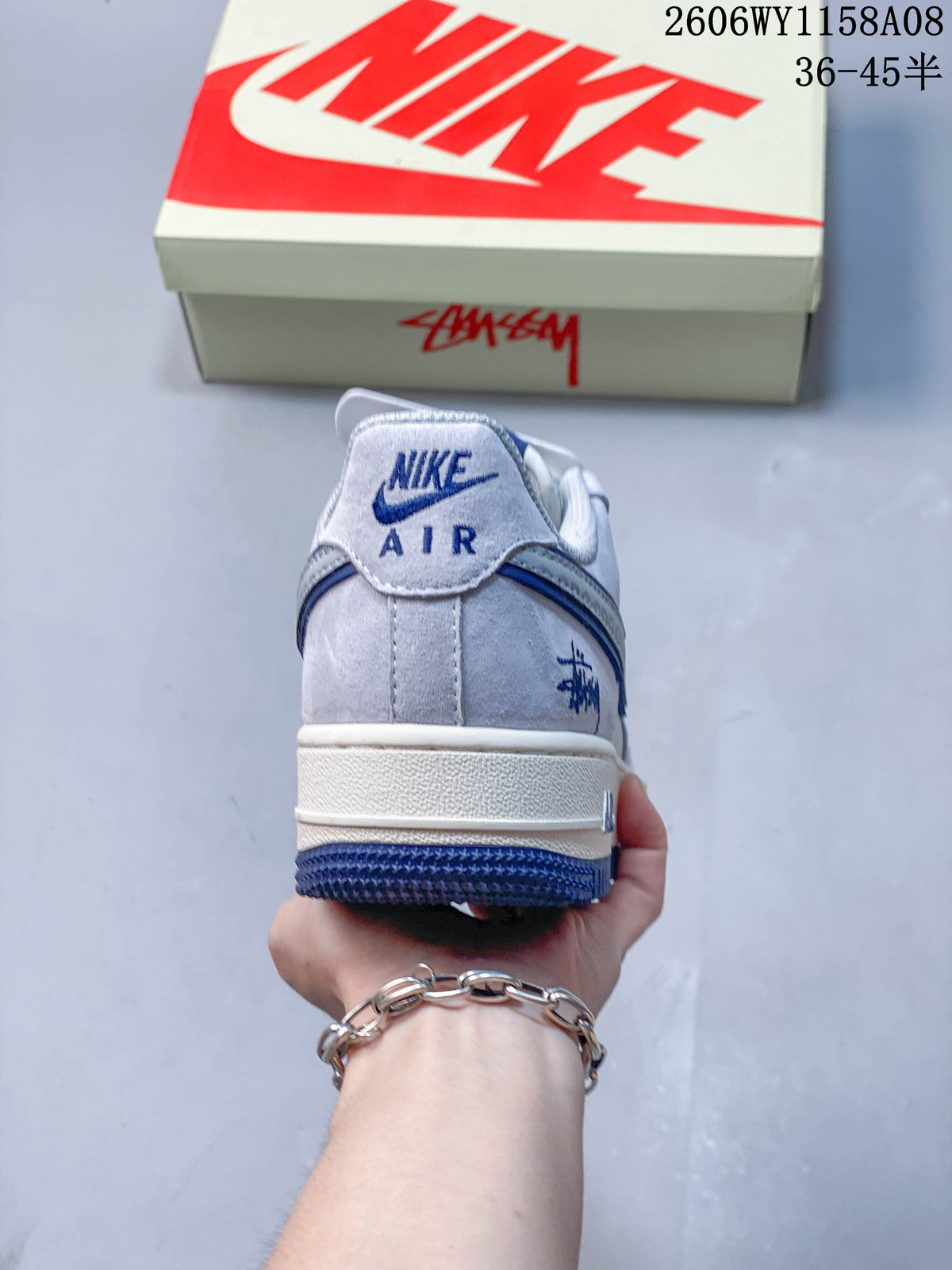 Rear view of a pale gray Nike Air Force 1 '07 sneaker with blue detailing