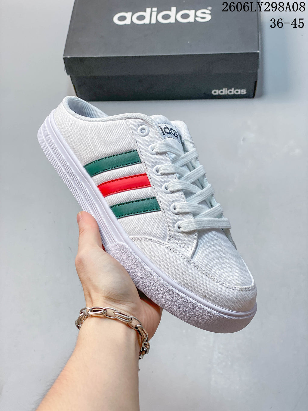 Close-up of a white adidas mule sneaker with green and red side stripes.