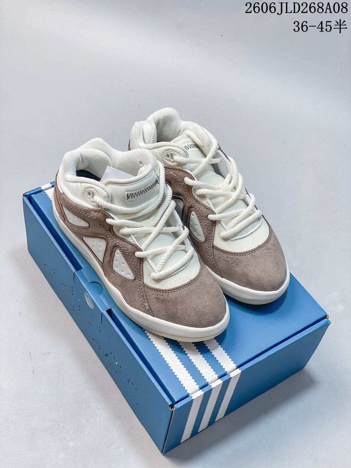 Pair of taupe and cream adidas Bad Bunny Badbo 1.0 sneakers on a blue box