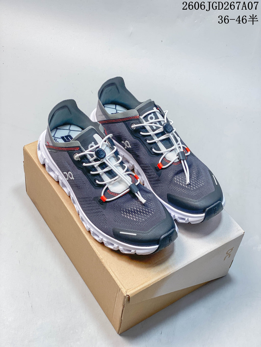 Pair of gray On Cloud 6 Coast sneakers with white soles and red accents, shown on a box.