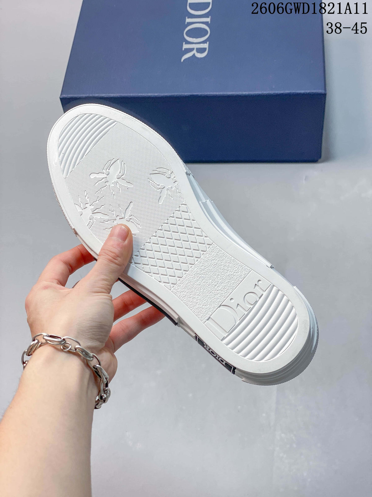 Underside of a sneaker showing a white patterned sole and Dior lettering, with a blue shoe box behind it