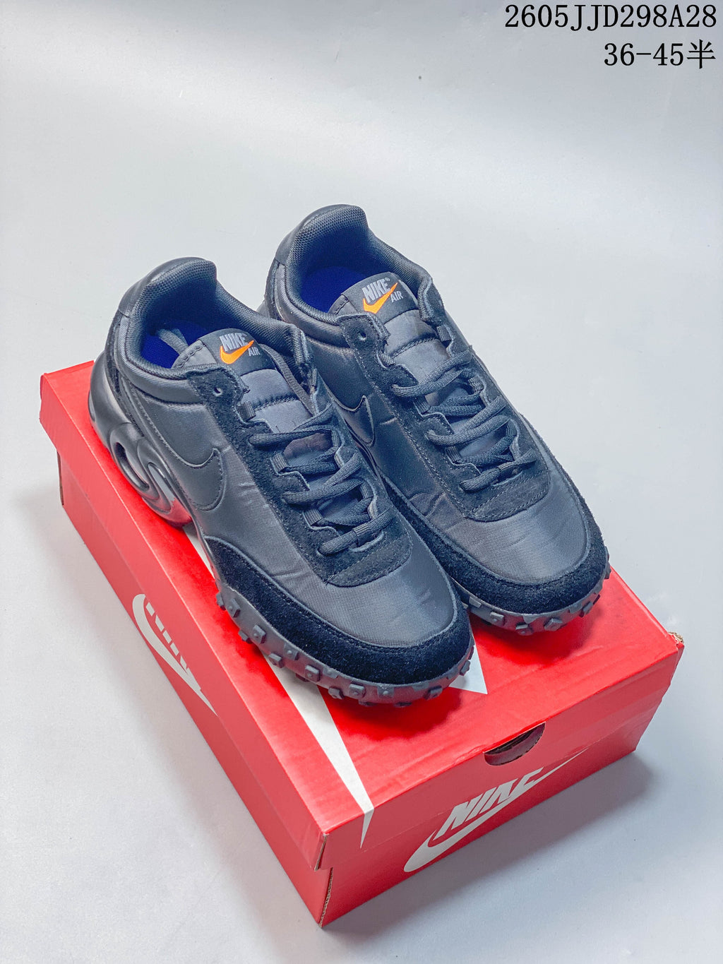 Pair of dark gray Nike Air Max Waffle SP sneakers displayed on a red box