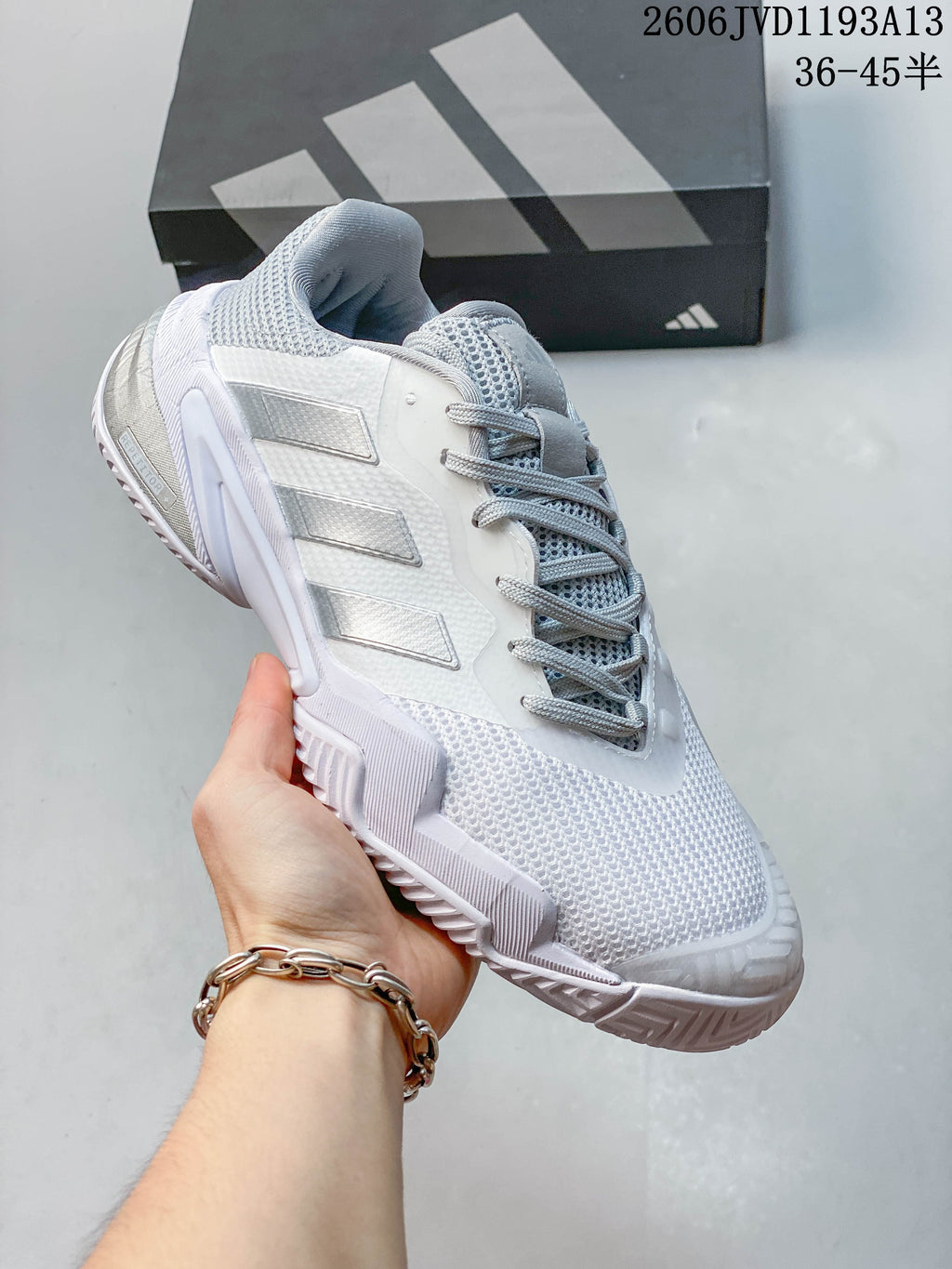 Side view highlighting the upper and silver-gray details of a white Adidas tennis shoe