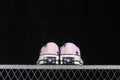 Rear view of pink low-top sneakers with blue star graphics and Converse All Star heel labels.