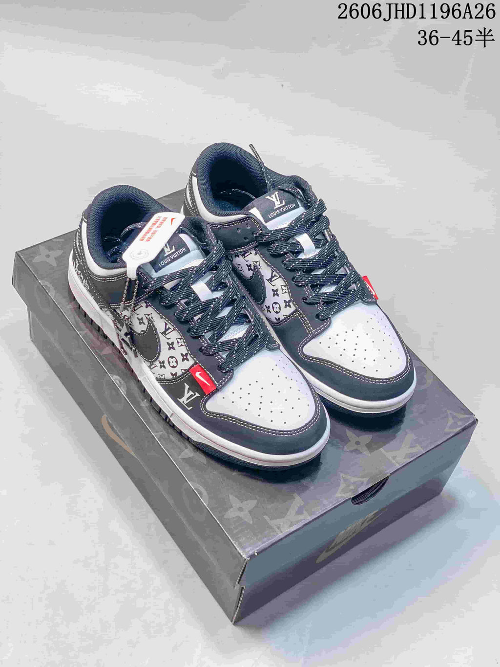 White and dark gray low-top sneakers with patterned side panels, red accent tabs, and a logo-patterned box.