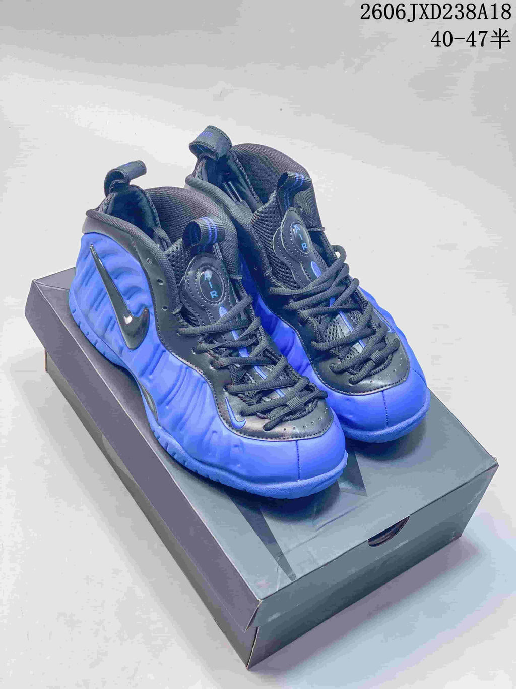 Pair of blue and dark Nike Foamposite Pro mid-top sneakers displayed on a box