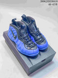 Pair of blue and dark Nike Foamposite Pro mid-top sneakers displayed on a box