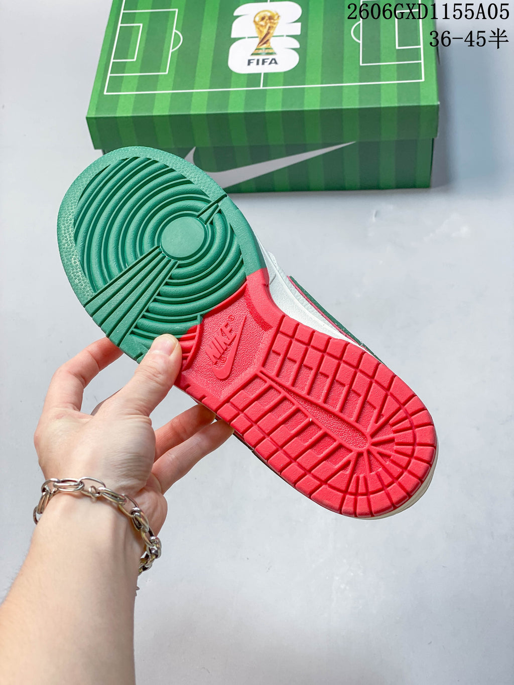 Green and red outsole of the Portugal-colorway sneakers, with a green soccer-field-themed box behind