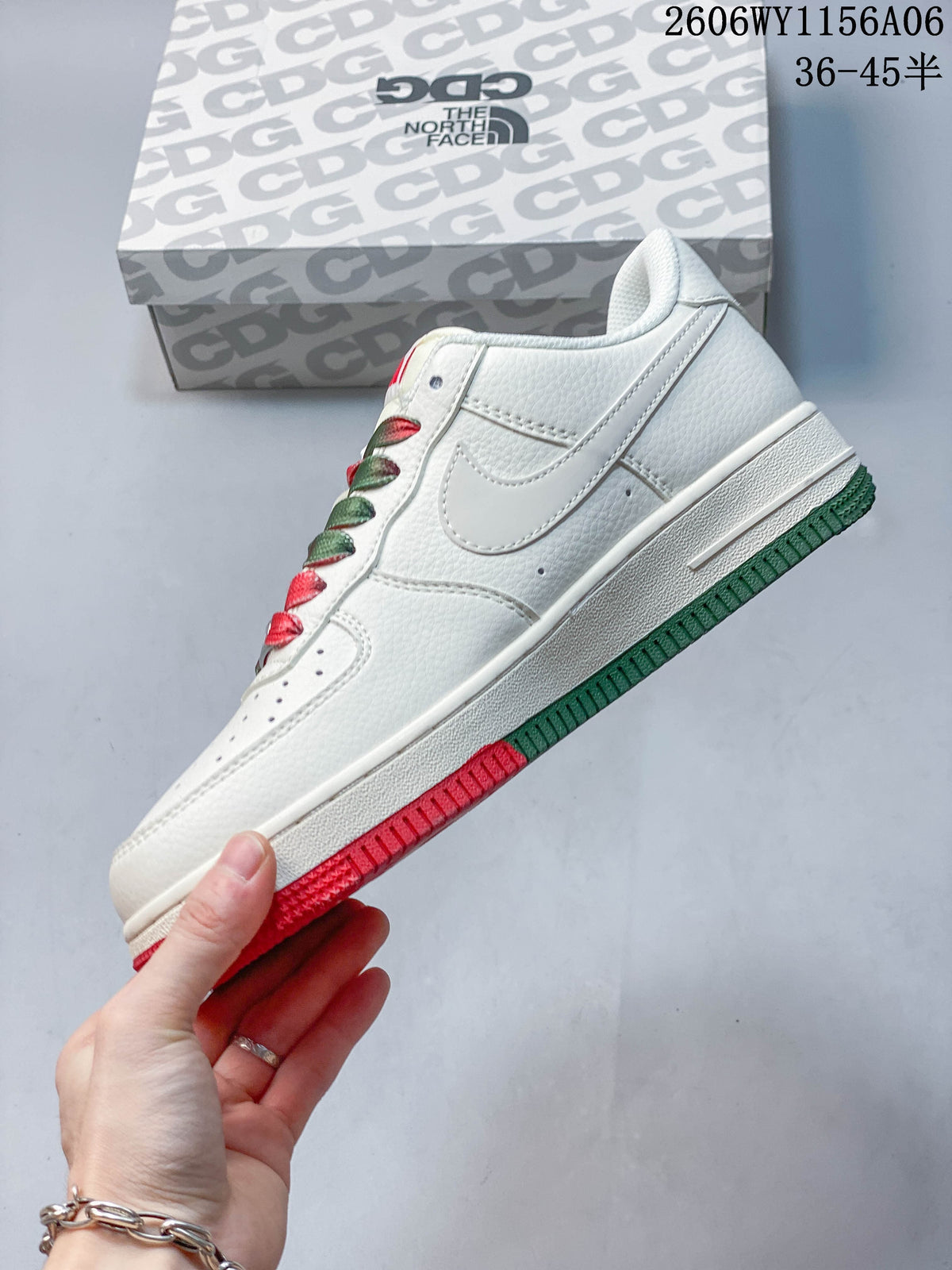 Side view of a white low-top sneaker with a Swoosh and red and green outsole accents