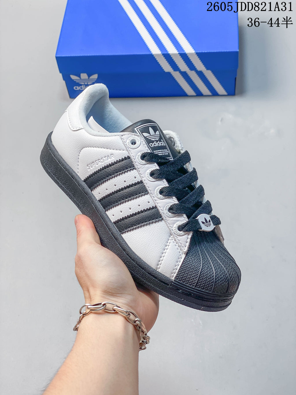 Close-up of a light Adidas Superstar with a dark shell toe, dark stripes and dark outsole.