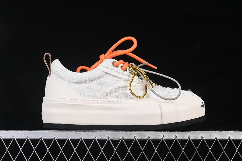 Side profile of a white textured low-top sneaker with a thick platform sole.