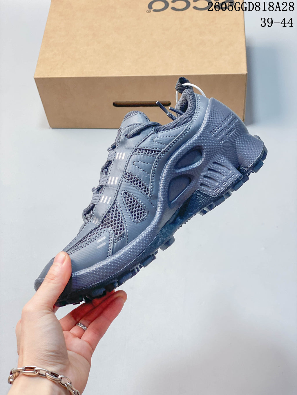 Side view of the gray sneaker with mesh panels and layered detailing
