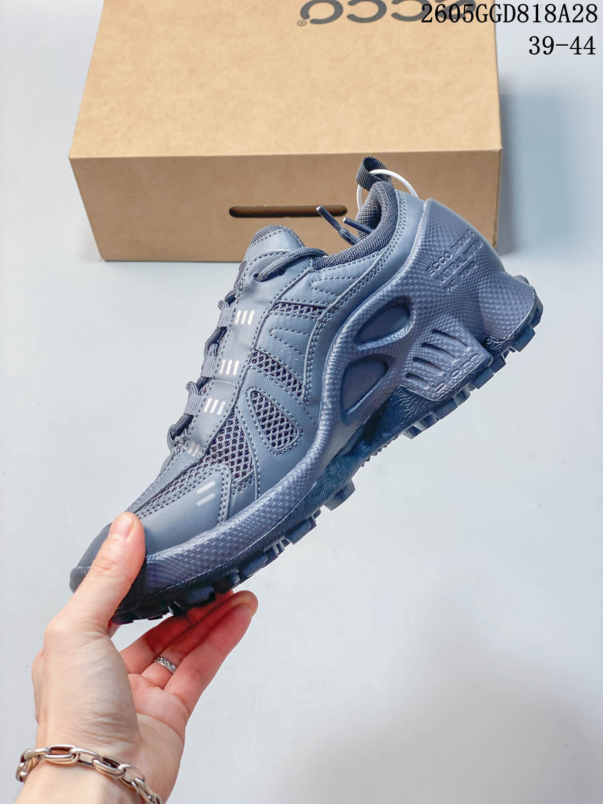 Side view of the gray sneaker with mesh panels and layered detailing