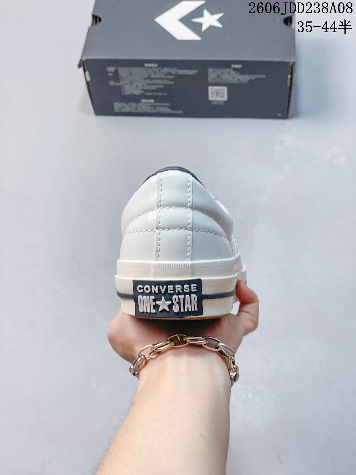 Rear view of a white Converse One Star sneaker with branded heel patch
