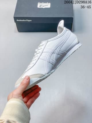 Side view of a white and silver ASICS Tiger Mexico 66 sneaker held in front of its shoebox; the image displays the size range 36–45 and code 2604JJD298A16.